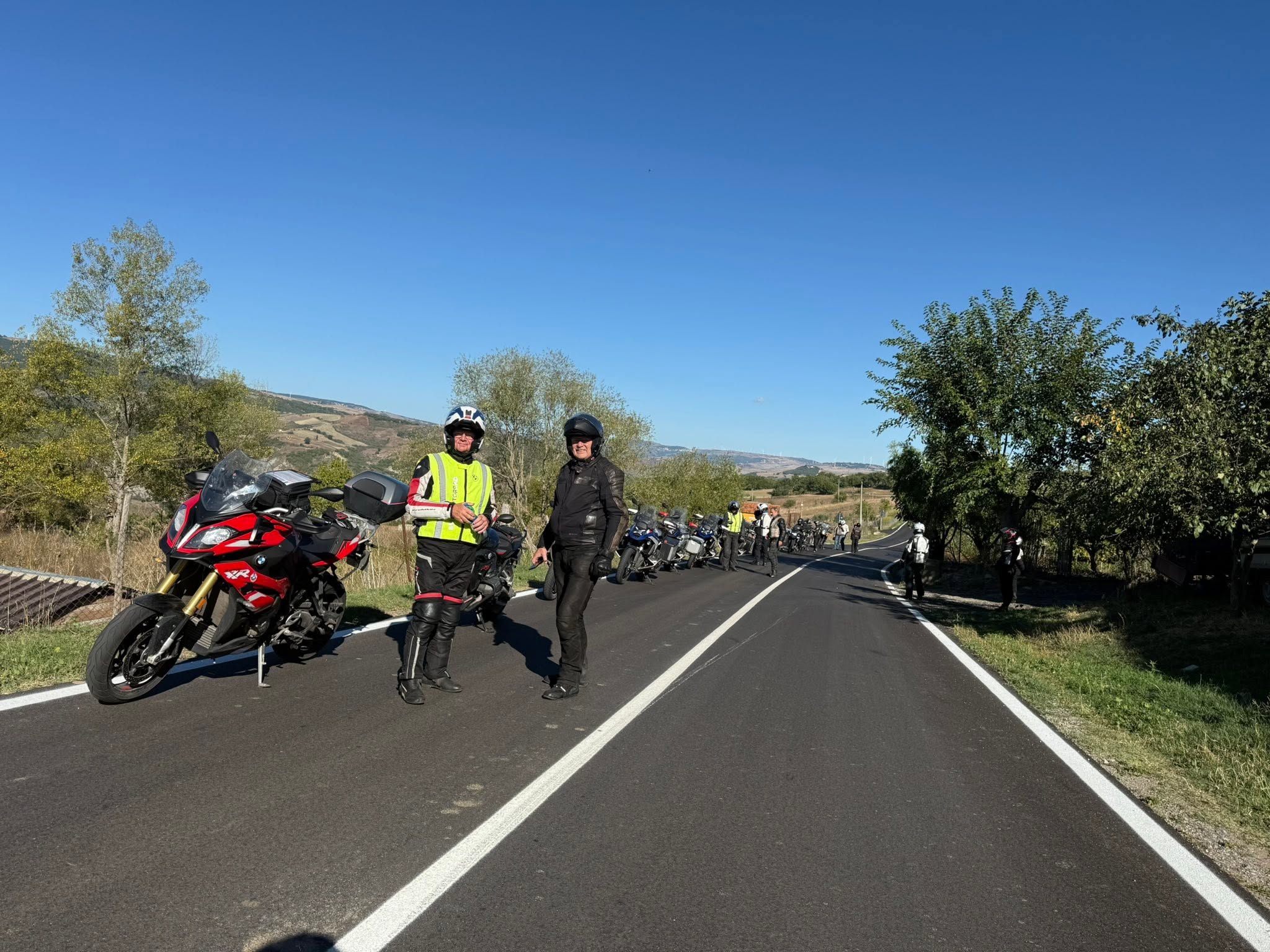 Motorradgruppe bei einem Fotostopp auf einer einsamen Straße in der Basilikata