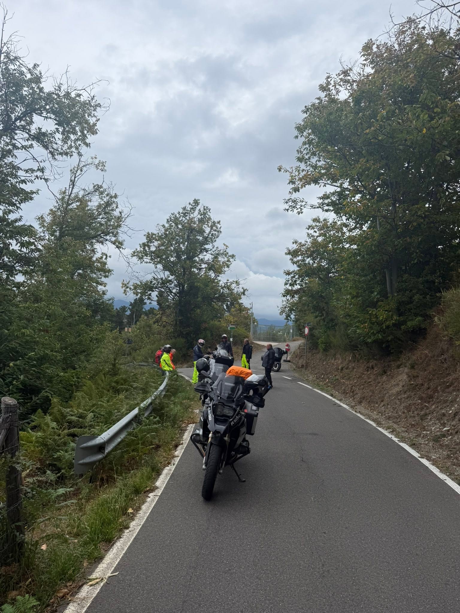 Motorradgruppe beim Anziehen der Regenkleidung auf einer schmalen Bergstraße